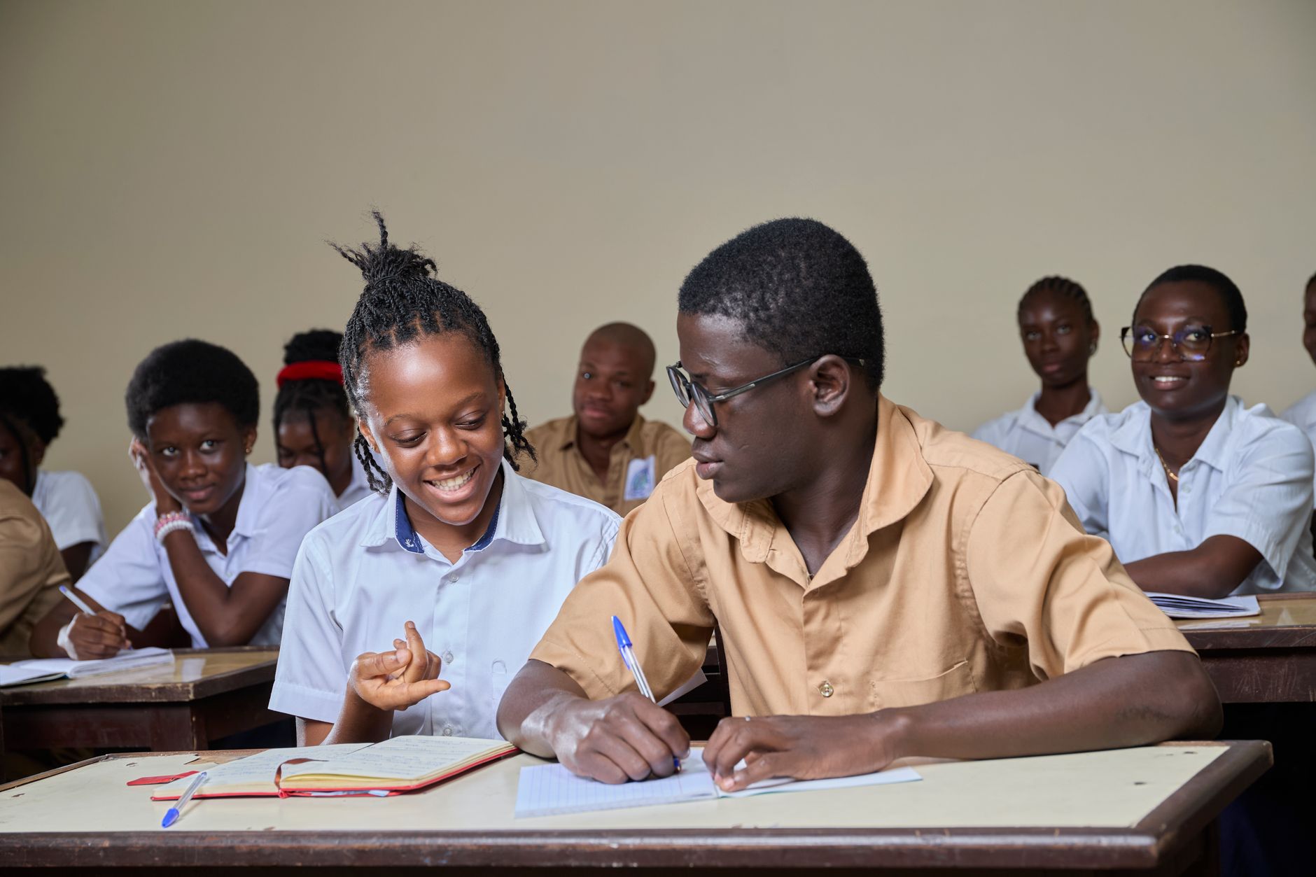 Two students working over a shared page in a classroom