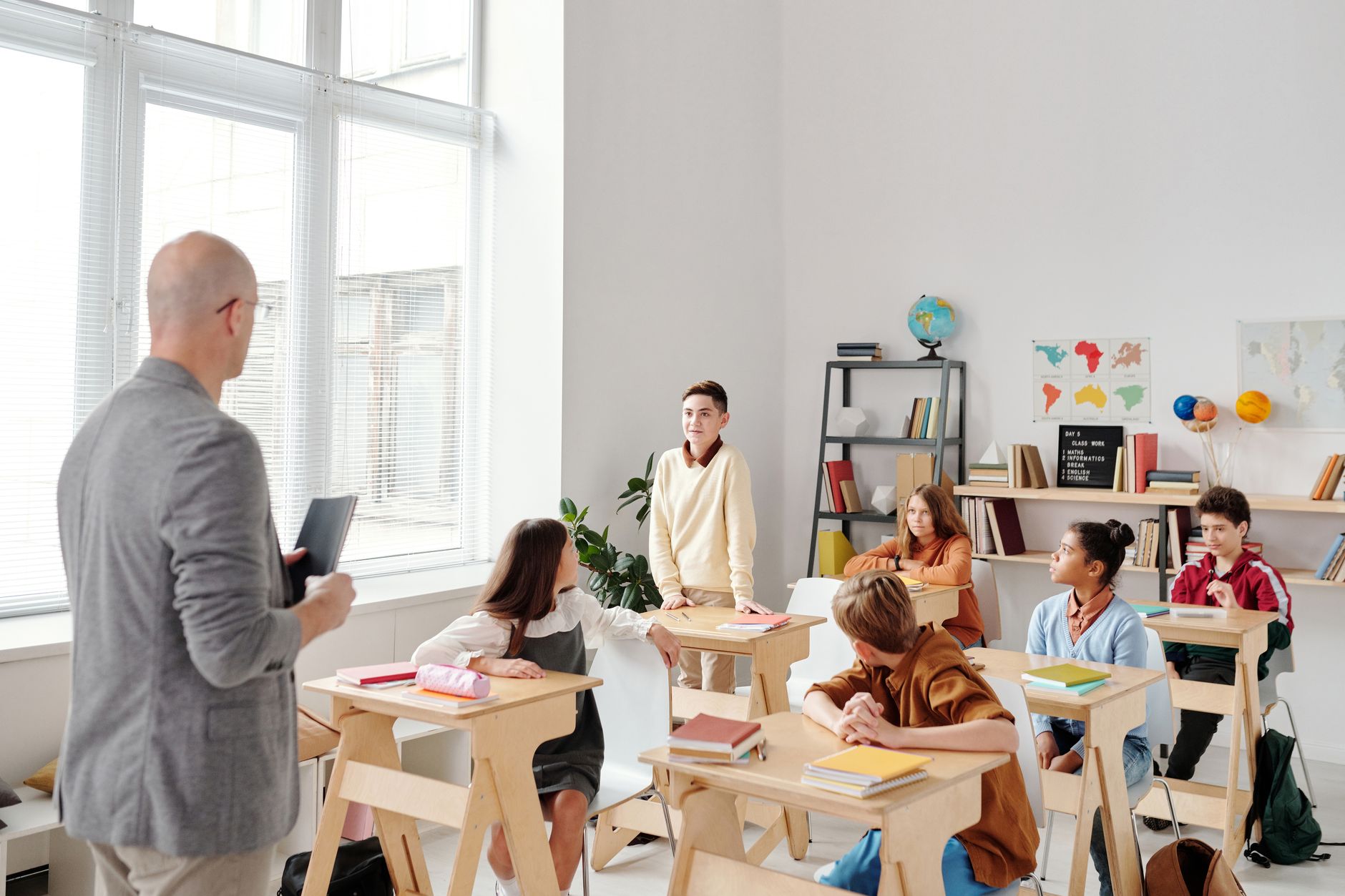 A seated group of students in a classroom, the teacher out of focus